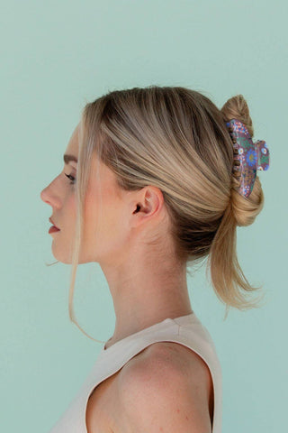 Woman with styled hair featuring a decorative hair accessory against a light green background
