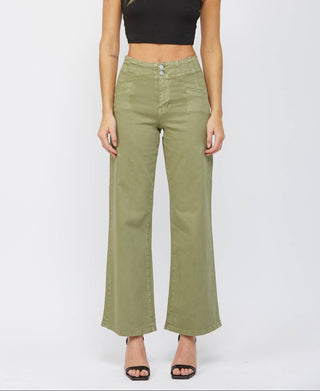 A woman modeling a black sleeveless crop top and olive green wide-leg jeans against a light gray studio background.