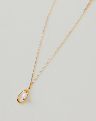 Gold necklace with a pendant on a light gray background