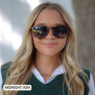 Woman wearing sunglasses and a green sweater with 'Midnight Ash' text.