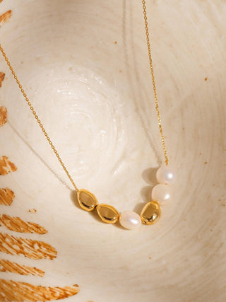 Gold necklace with pearls on a shell background
