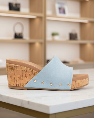 Wedge sandal with cork wedge and light blue fabric strap on a white background