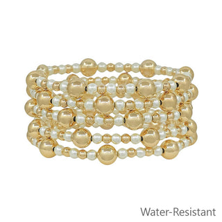 Set of gold and pearl beaded bracelets on a white background