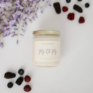 Candle jar labeled 'My Oh My' with berries and flowers on a light background