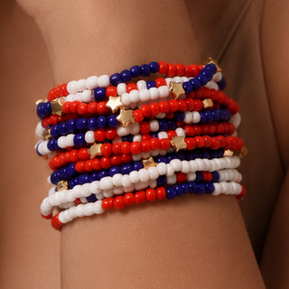 Stack of red, white, and blue beaded bracelets on a wrist against a neutral background