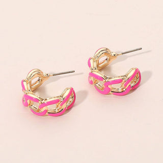 Gold hoop earrings with pink accents on a beige background