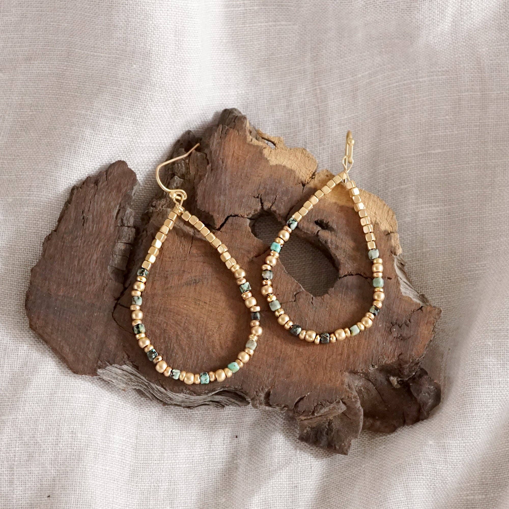 Beaded hoop earrings on a piece of wood with a neutral background