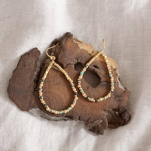 Beaded hoop earrings on a piece of wood with a neutral background