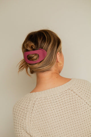 Person wearing a pink hair clip with a neutral background