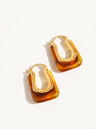 Gold and amber hoop earrings on a white background