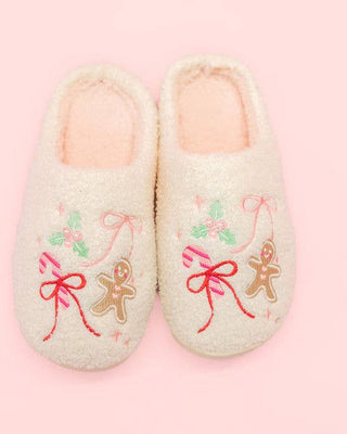 Pair of slippers with gingerbread men and bows on a pink background