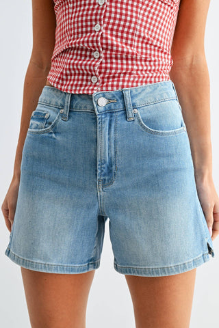 Person wearing a red and white checkered top and blue denim shorts on a white background