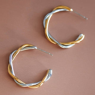 Pair of gold and silver hoop earrings on a brown background