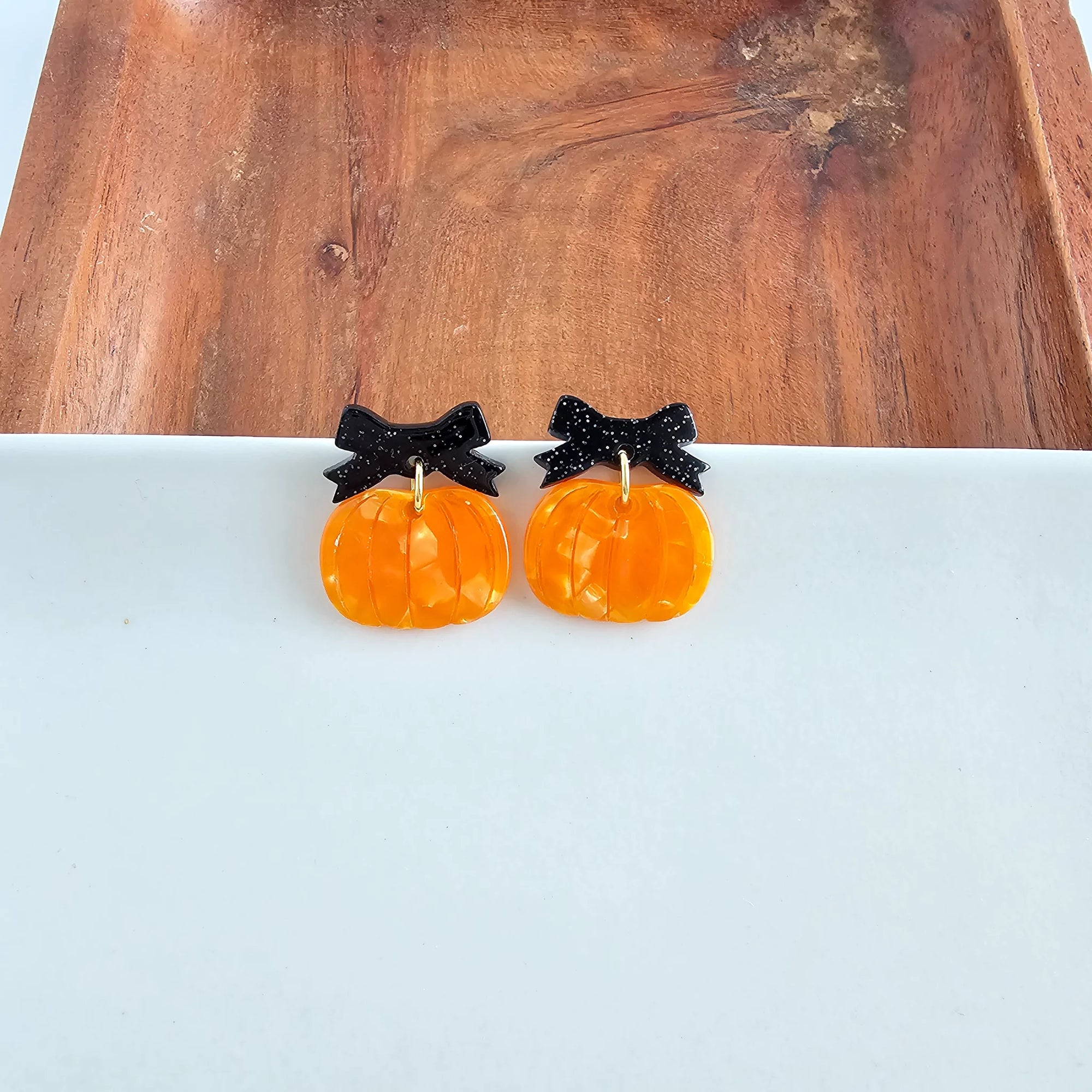 Orange pumpkin dangle earrings with a black bow